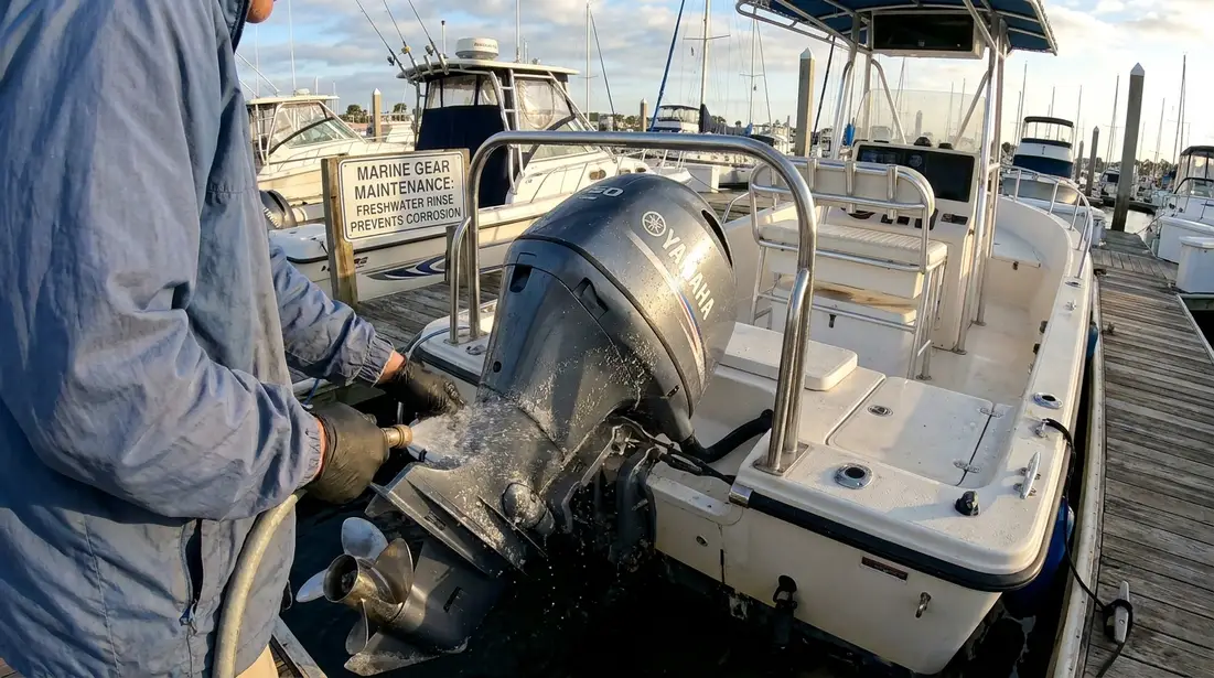 Boat owner rinsing saltwater from outboard engine and deck hardware
